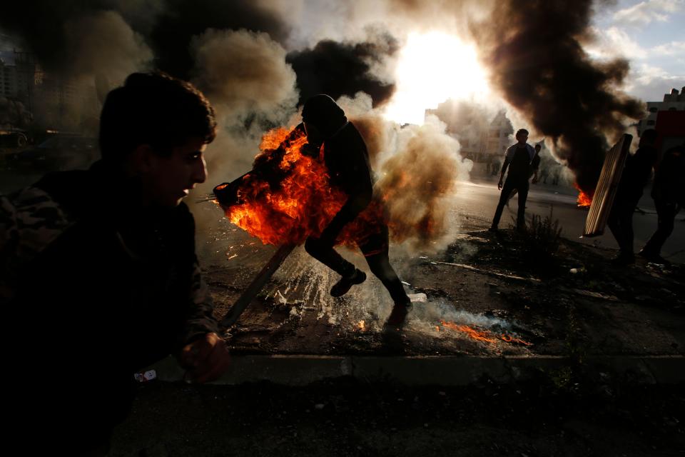 <p>A Palestinian protester runs after catching fire during clashes with Israeli troops at a protest against President Donald Trump’s decision to recognize Jerusalem as the capital of Israel, near the Jewish settlement of Beit El, near the West Bank city of Ramallah on Dec. 7, 2017. (Photo: Abbas Momani/AFP/Getty images) </p>