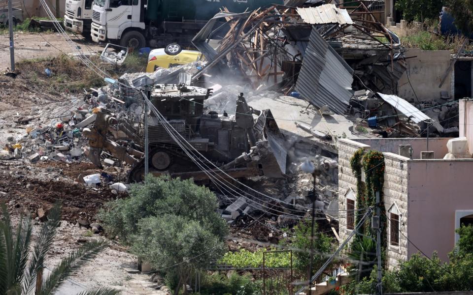 An Israeli army bulldozer operates amid the rubble of a demolished building during a raid in the occupied West Bank town of Deir al-Ghusun near Tulkarem on May 4, 2024.