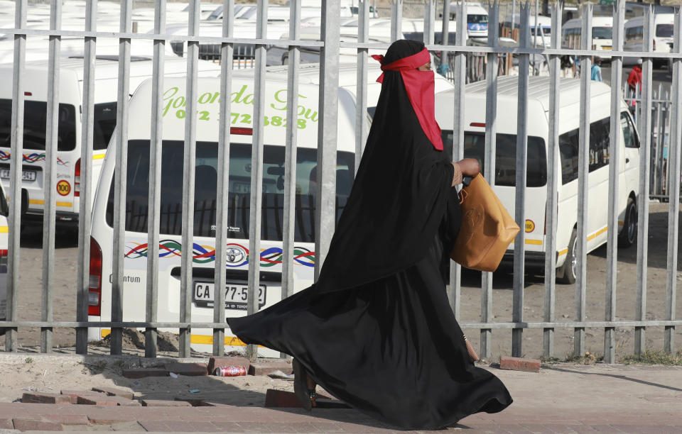 A woman wears a face mask at a taxi rank in Bellville a suburb of Cape Town, South Africa, Thursday, May 21, 2020, during an eased lockdown in the country to prevent the spread of COVID-19. With dramatically increased community transmissions, Cape Town has become the centre of the coronavirus outbreak in South Africa and the entire continent. (AP Photo/Nardus Engelbrecht)