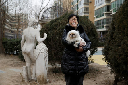 Hu Yujie poses for pictures with her Pekingese dog, Xiaobai, outside her house in Beijing, China, January 7, 2018. Picture taken January 7, 2018. REUTERS/Thomas Peter