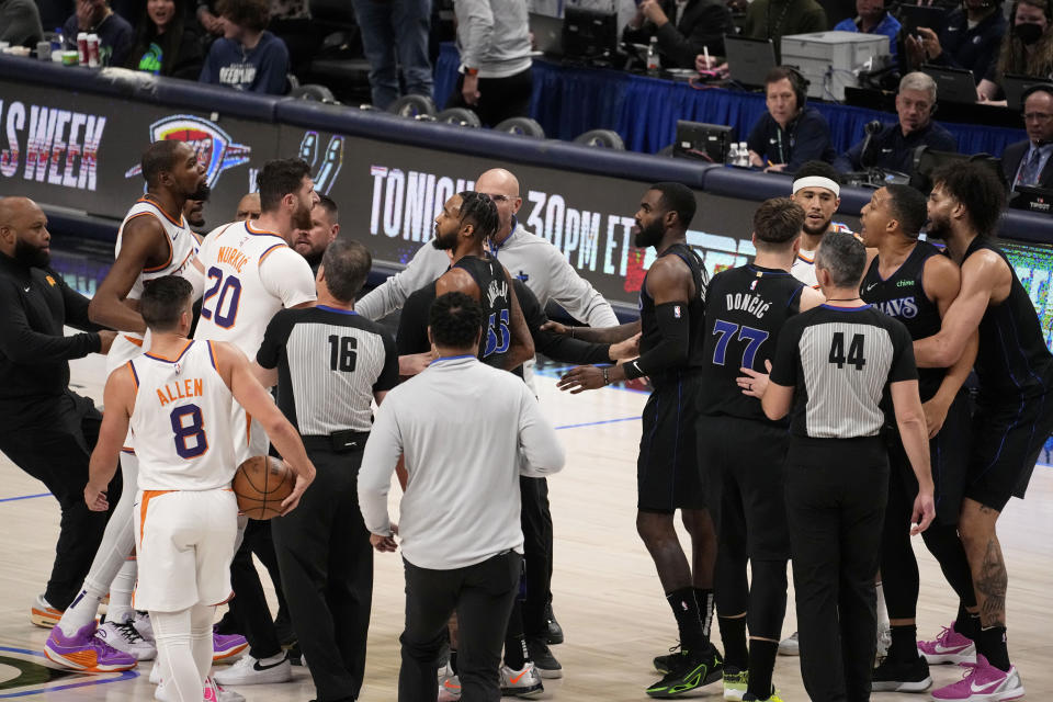 Team staff, players and officials run onto the court after an on court incident between Phoenix Suns' Kevin Durant, second from top left, and Dallas Mavericks' Grant Williams, second from top right, in the first half of an NBA basketball game in Dallas, Wednesday, Jan. 24, 2024. (AP Photo/Tony Gutierrez)