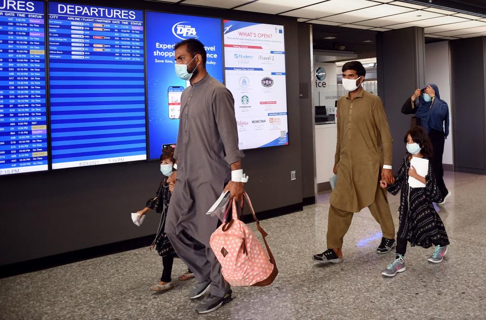 Afghan refugees walk to board a bus after arriving on a flight at Dulles International Airport in Chantilly, Virginia on August 23, 2021. (Olivier Douliery/AFP via Getty Images)