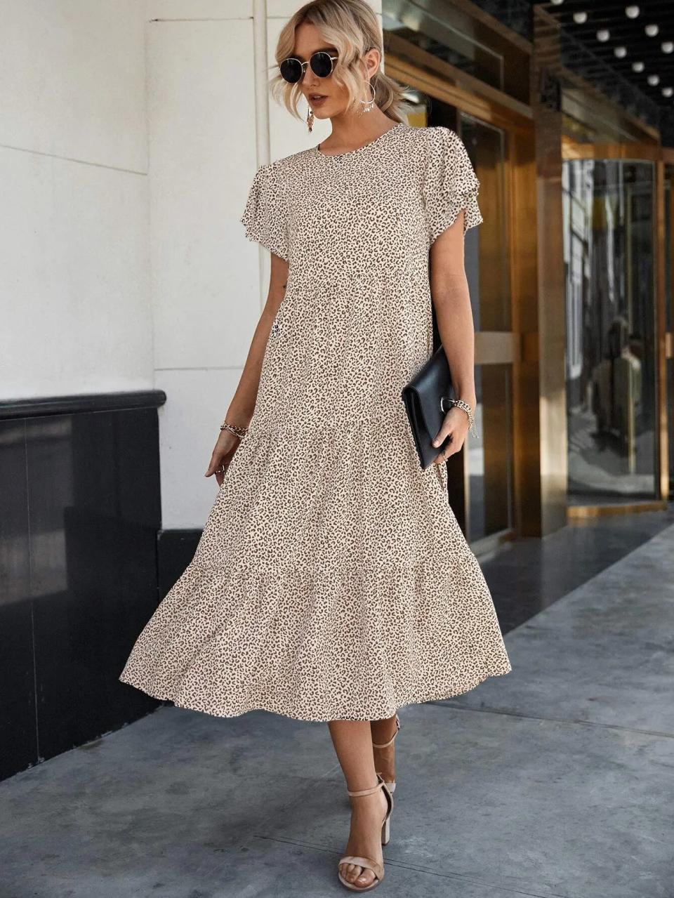 Person in a mid-length dress with short sleeves and a clutch, posing on a sidewalk