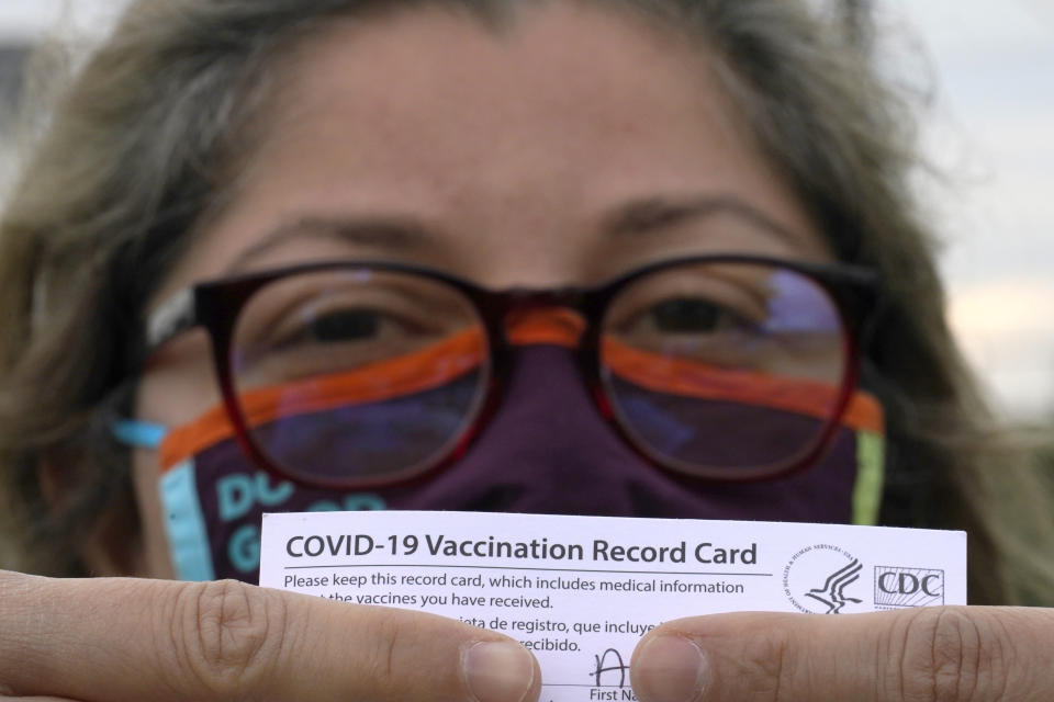 Alejandra poses with her vaccination card after getting her second Moderna COVID-19 shot Monday April 19, 2021, in Pasadena, Texas. Alejandra, a dentist who also lives in Monterrey, Mexico, said she decided to seek a vaccine in the U.S. shortly after losing her mother to COVID-19 in February. Many people with the means from Latin America are traveling thousands of miles to get the COVID-19 vaccine in the United States because supplies are limited in their own countries. (AP Photo/David J. Phillip)