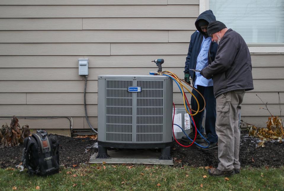 HVAC technicians do some work on a heat pump at a home in Fishers, Ind. As electricity bills and emissions continue to go up, homeowners are exploring electric heat pumps as a way to heat and cool their homes and help the environment and their wallets.