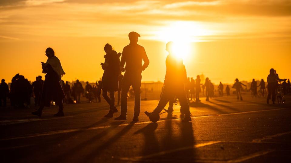 Menschen spazieren während des Sonnenuntergangs bei frühlingshaften Temperaturen auf dem Tempelhofer Feld in Berlin.