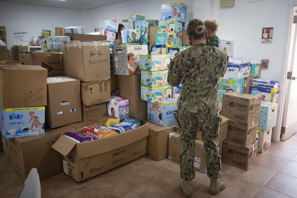 A soldier holds a child, one of the evacuees from Afghanistan in a storage facility with boxes of diapers at the Naval Station in Rota, southern Spain, Tuesday Aug. 31, 2021. The United States completed its withdrawal from Afghanistan late Monday, ending America's longest war. (AP Photo/ Marcos Moreno)