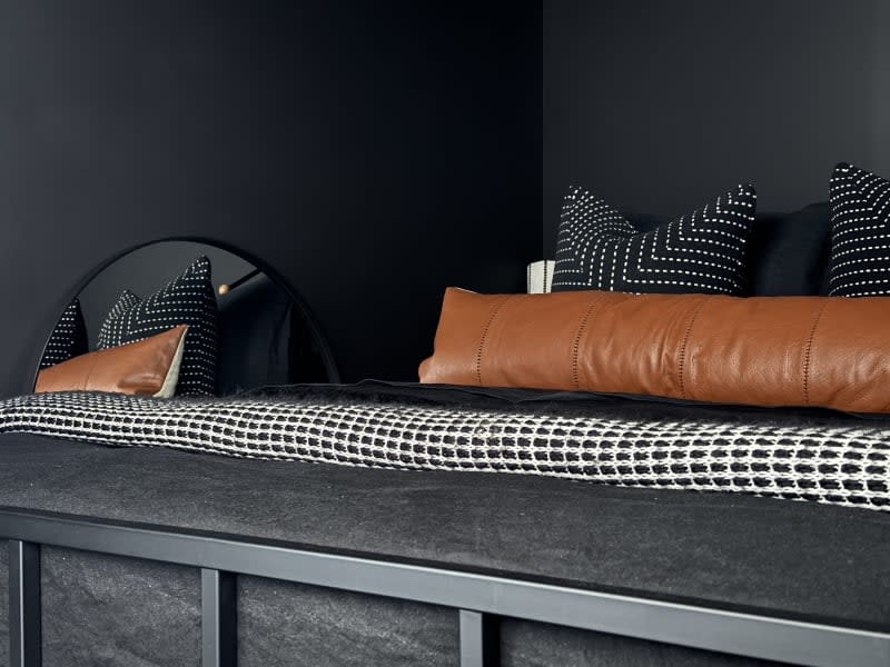 Black bedroom with decorative pillows.