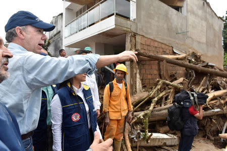 Colombia's President Juan Manuel Santos (L) gestures while visiting a flooded area after heavy rains caused several rivers to overflow, pushing sediment and rocks into buildings and roads in Mocoa, Colombia April 1, 2017. Cesar Carrion/Colombian Presidency/Handout via Reuters