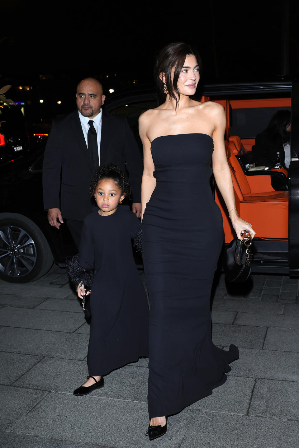 Kylie Jenner wearing a long black dress in Paris with Stormi