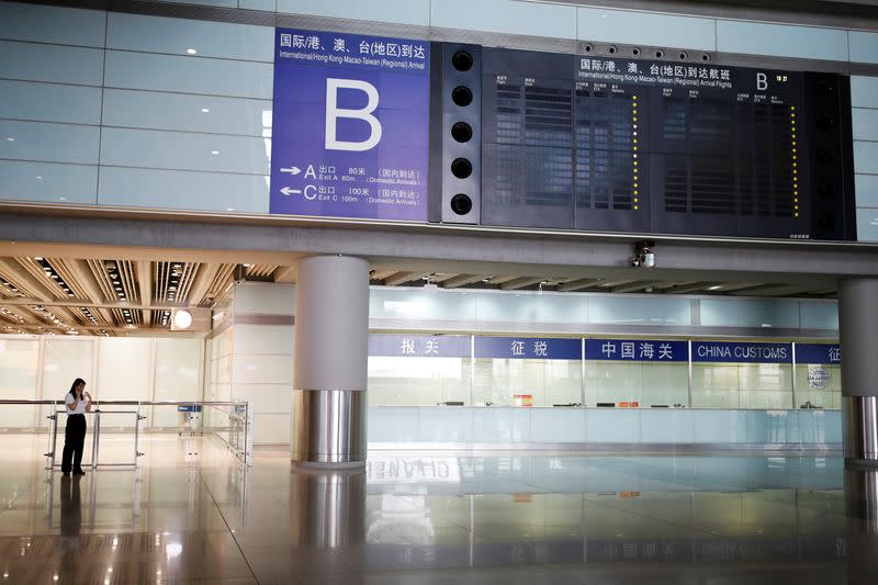 Woman uses a mobile phone near an information display at Beijing Capital International Airport, in Beijing