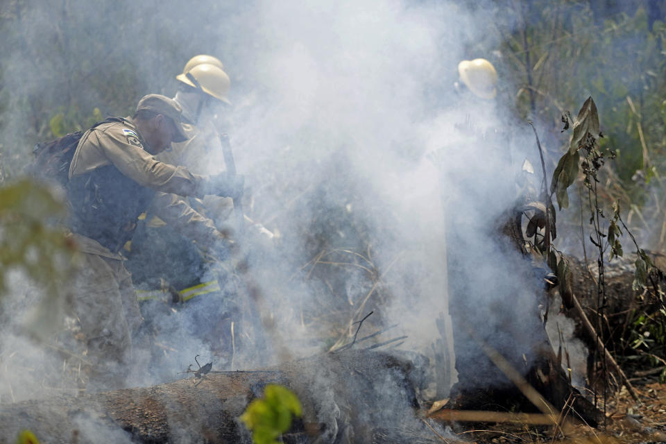 Firefighters work to put out forest fires along the road to Jacunda National Forest near the city of Porto Velho in Rondonia state, in the Vila Nova Samuel region, part of Brazil's Amazon, Sunday, Aug. 25, 2019. Leaders of the Group of Seven nations said Sunday they were preparing to help Brazil fight the fires burning across the Amazon rainforest and repair the damage even as tens of thousands of soldiers were being deployed to fight the blazes that have caused global alarm. (AP Photo/Eraldo Peres)