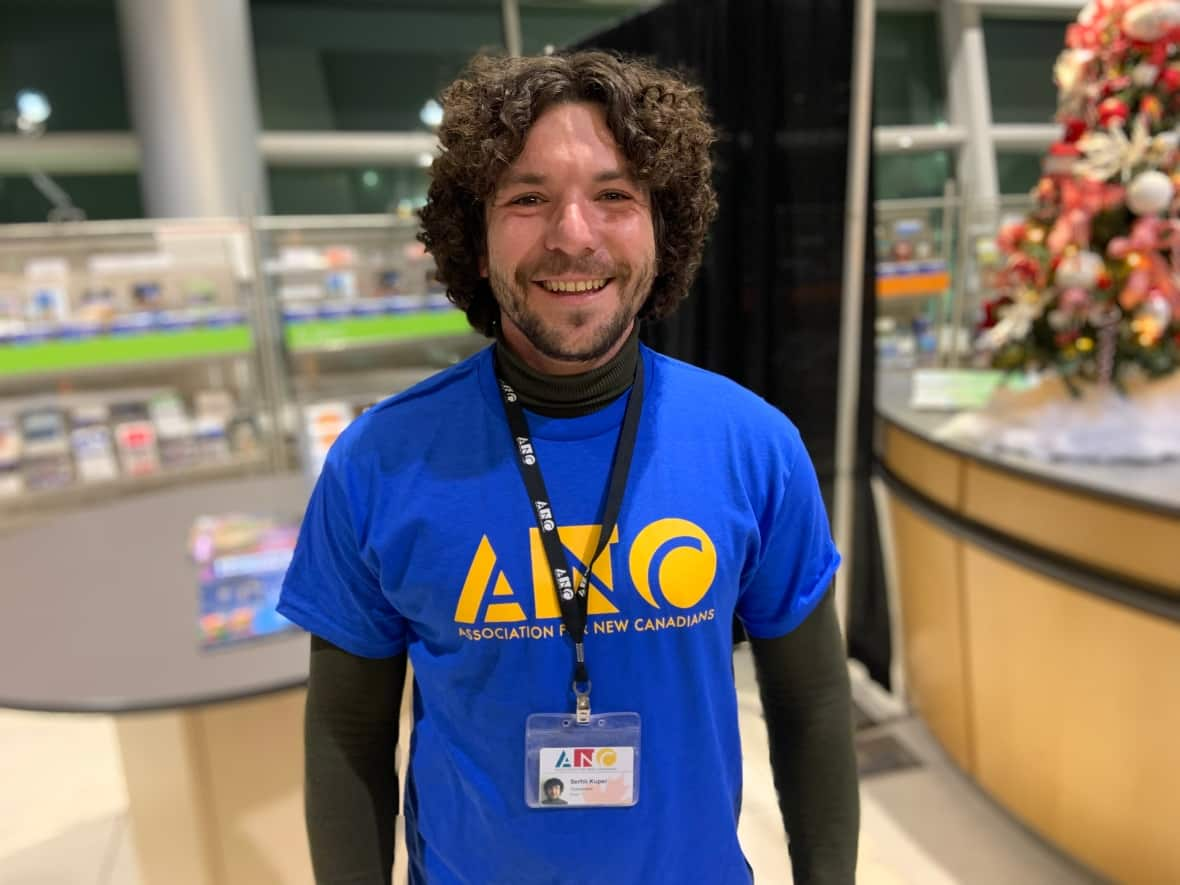 Serhii Kuper, a Ukrainian who arrived on a government-chartered flight in June, now works for the Association for New Canadians, helping other Ukrainians get settled. On Tuesday, he was waiting to be reunited with his aunt and grandmother. (Darrell Roberts/CBC - image credit)