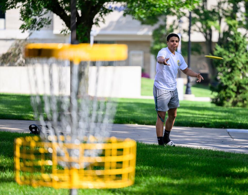 Jon LaBelle, a senior at Siena Heights University from Armada, tosses a disc toward one of the disc golf baskets Friday on the SHU campus.