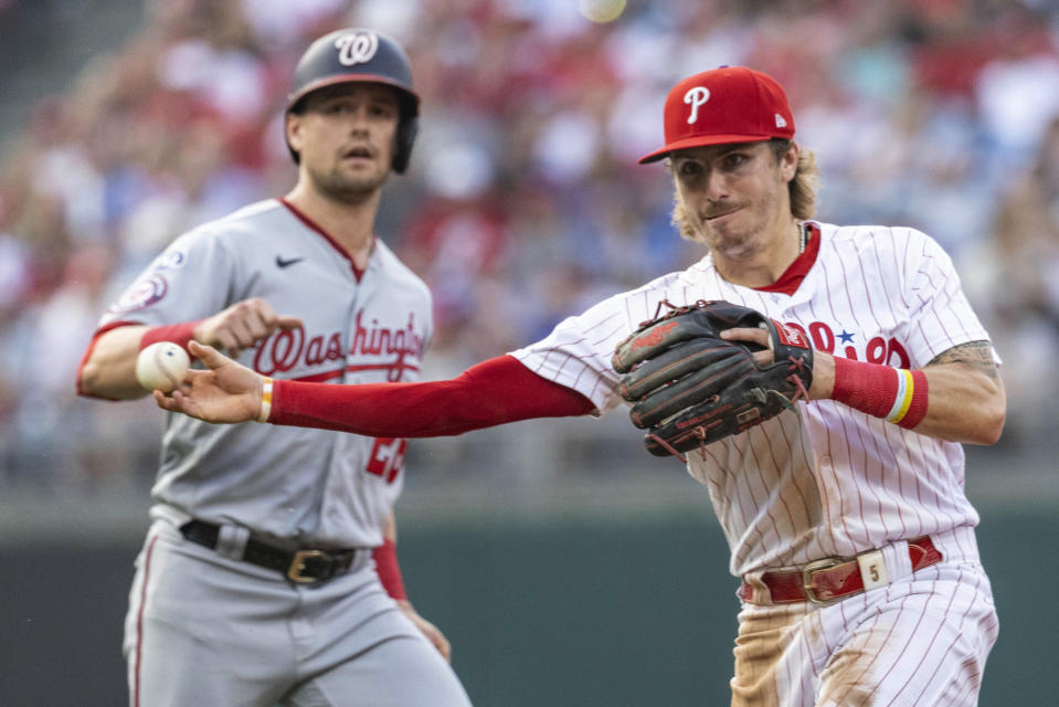 Philadelphia Phillies second baseman Bryson Stott throws to first on a double play on Washington Nationals' Luis Garcia, after making the out on Lane Thomas, left, during the third inning of a baseball game Friday, June 30, 2023, in Philadelphia. (AP Photo/Laurence Kesterson)
