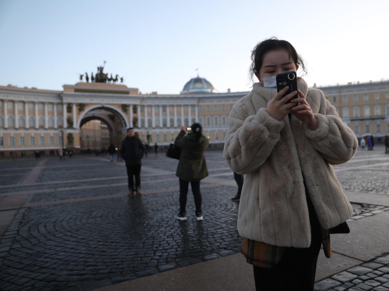 Chinese tourists wearing masks take pictures of the State Hermitage Museum in St Petersburg, Russia