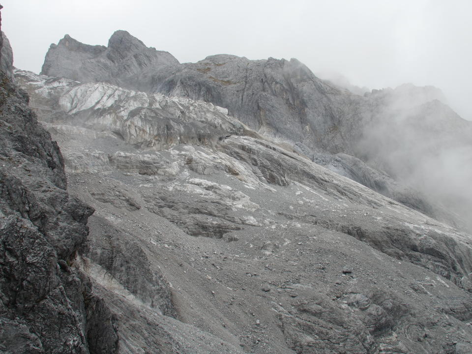 This Sept. 21, 2018 photo shows the lower edge of the Baishui Glacier No.1 above grey rocks previous covered in ice in Jade Dragon Snow Mountain in the southern province of Yunnan in China. Scientists say the glacier is one of the fastest melting glaciers in the world due to climate change at its relative proximity to the Equator. It has lost 60 percent of its mass and shrunk 250 meters since 1982. (AP Photo/Sam McNeil)