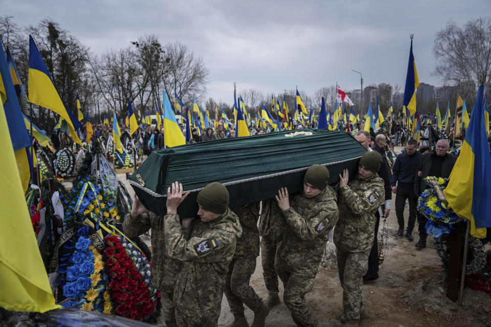 Ukrainian servicemen carry the coffin of their comrade Andrii Neshodovskiy during the funeral ceremony at the cemetery in Kyiv, Ukraine, Saturday, March 25, 2023. (AP Photo/Evgeniy Maloletka)