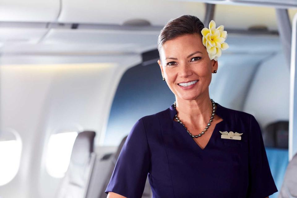 A smiling flight attendant on a Hawaiian Airlines flight