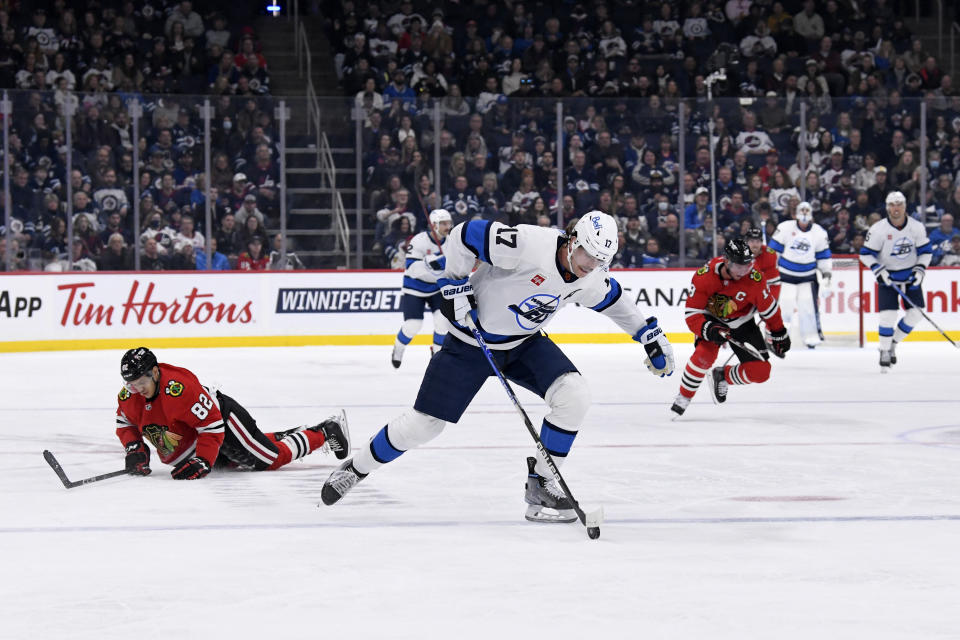 Winnipeg Jets' Adam Lowry (17) heads off on a breakaway to score after stripping the puck off Chicago Blackhawks' Caleb Jones (82) during the second period of NHL hockey game action in Winnipeg, Manitoba, Saturday, Nov. 5, 2022. (Fred Greenslade/The Canadian Press via AP)