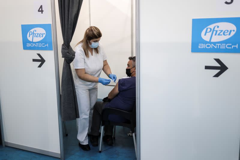 A healthcare worker administers a dose of Pfizer's coronavirus disease (COVID-19) vaccine to a man at Belgrade Fair vaccination center in Belgrade