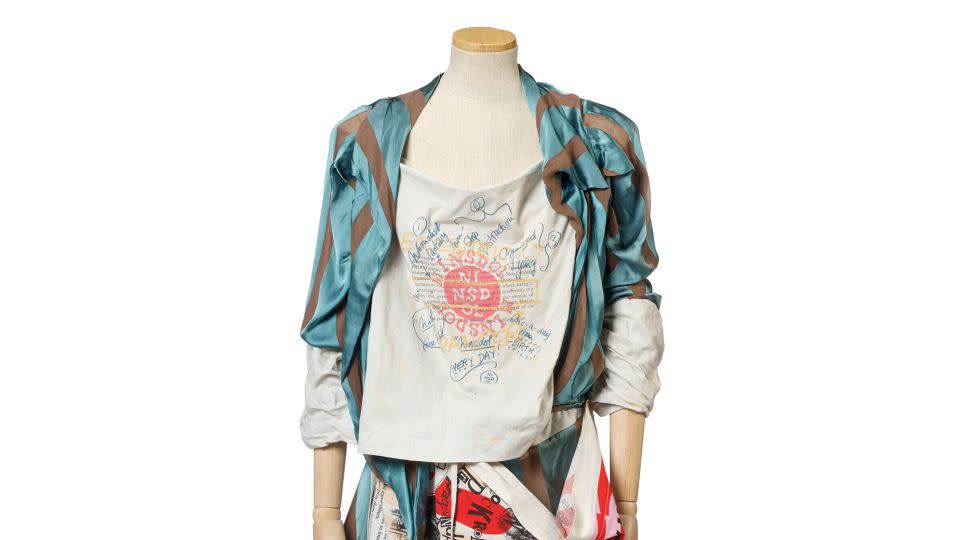 "Propaganda," Autumn/Winter 2005-2006. The look features a dress with a blue and white striped blouse and printed propaganda modesty panel and apron. - Courtesy Christie's