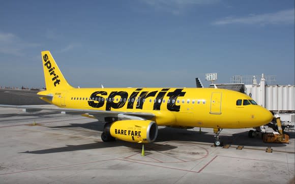 A yellow Spirit Airlines A319 jet parked at an airport gate.