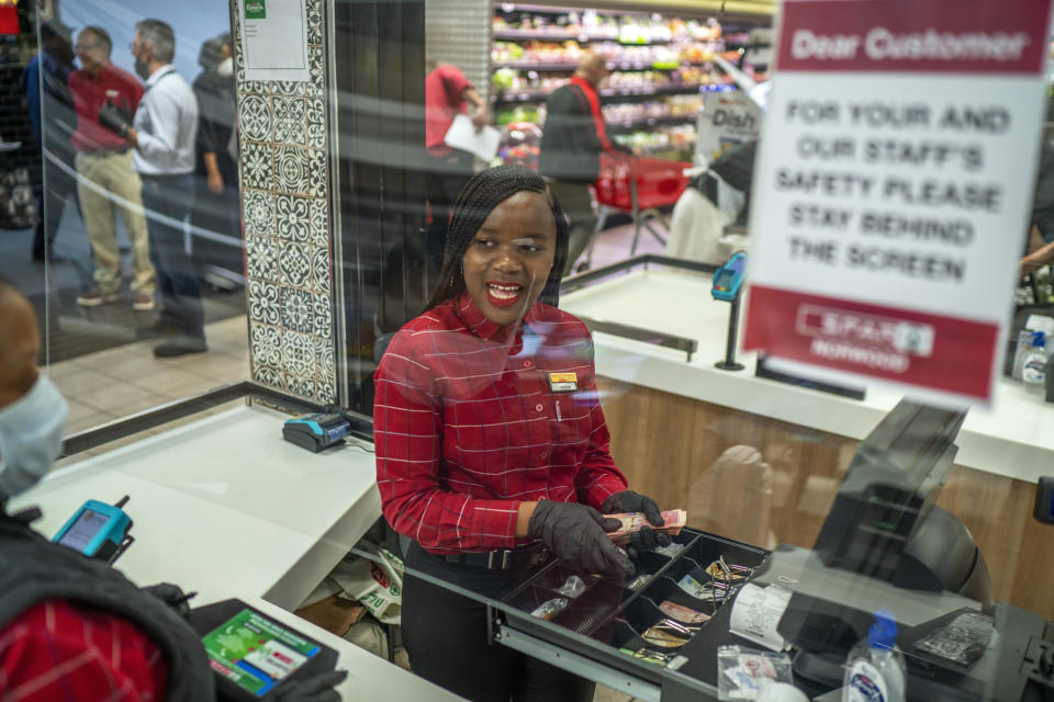 In this March 30, 2020, photo, Zandile Mlotshwa, 21, cashier at Spar supermarket in the Norwood suburb of Johannesburg, counts her cash at the end of her shift. From South Africa to Italy to the U.S., grocery workers — many in low-wage jobs — are manning the front lines amid worldwide lockdowns, their work deemed essential to keep food and critical goods flowing. (AP Photo/Jerome Delay)