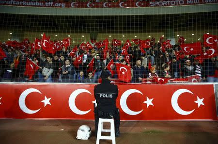 A policeman stands guard in front of supporters of Turkey during their international friendly soccer match against Greece at Basaksehir Fatih Terim stadium in Istanbul, Turkey in this November 17, 2015 file photo. REUTERS/Osman Orsal/Files