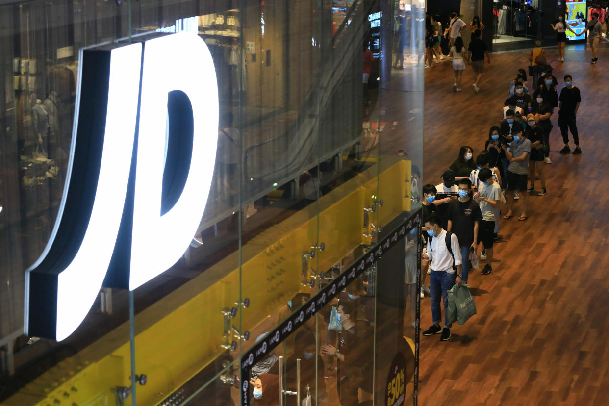 SINGAPORE - JUNE 20:  Shoppers wearing protective masks wait to enter JD Sports, a sneaker and sport fashion retailer at Orchard Road on June 20, 2020 in Singapore. From June 19, Singapore started to further ease the coronavirus (COVID-19) restrictions by allowing social gatherings up to five people, re-opening of retail outlets and dining in at food and beverage outlets, subjected to safe distancing. Parks, beaches, sports amenities and public facilities in the housing estates will also reopen. However, large scale events, religious congregations, libraries, galleries and theatres will remain closed.  (Photo by Suhaimi Abdullah/Getty Images)