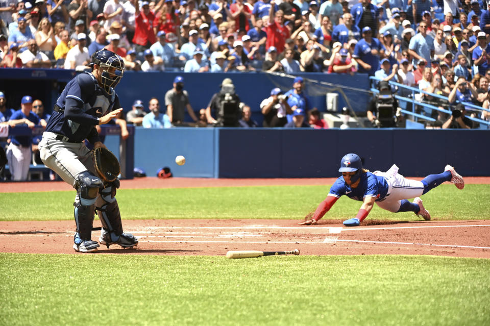 Toronto Blue Jays' starting pitcher Bo Bichette slides safely into home ahead of the throw to Tampa Bays Rays' catcher Rene Pinto during the first inning of a baseball game, Saturday, July 2, 2022 in Toronto. (Jon Blacker/The Canadian Press via AP)