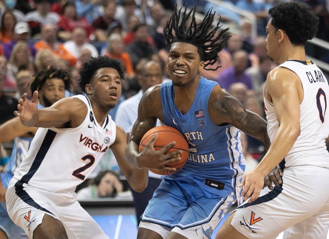 North Carolina’s Caleb Love (2) drives against Virginia’s Kihei Clark (0) and Reece Beekman (2) in the second half during the third round of the ACC Tournament on Thursday, March 9, 2023 at the Greensboro Coliseum in Greensboro, N.