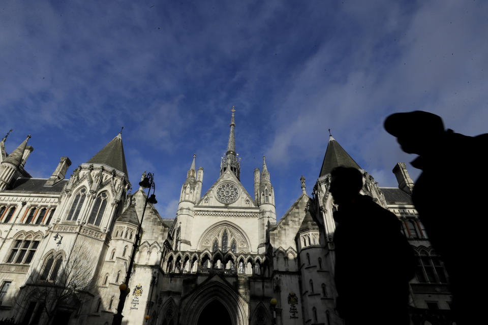 Pedestrian pass by The Royal Courts Of Justice, in London, Tuesday, Jan. 19, 2021. Meghan, the Duchess of Sussex will ask a High Court judge to rule in her favour in her privacy action against the Mail on Sunday over the publication of a handwritten letter to her estranged father. The case will be heard remotely due to the pandemic. (AP Photo/Kirsty Wigglesworth)