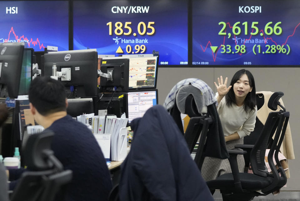 A currency trader gestures near the screens showing the Korea Composite Stock Price Index (KOSPI), right, at the foreign exchange dealing room of the KEB Hana Bank headquarters in Seoul, South Korea, Wednesday, Feb. 14, 2024. Asian shares declined Wednesday, after disappointing U.S. inflation data sent shares sliding on Wall Street, raising prospects that interest rates will stay high for longer. (AP Photo/Ahn Young-joon)