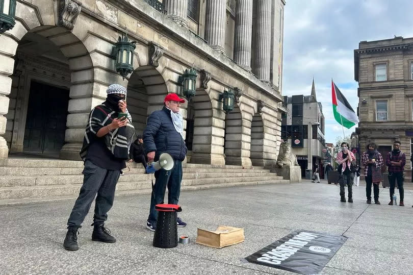 Palestine protestors speaking on megaphone outside Nottingham Council House, with Palestine flag visible on right