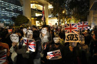 Protesters wear masks of Simon Cheng, a Hong Kong British Consulate employee who was detained in China, as they gather for a rally outside of the British Consulate in Hong Kong, Friday, Nov. 29, 2019. Hong Kong police ended their blockade of a university campus Friday after surrounding it for 12 days to try to arrest anti-government protesters holed up inside. (AP Photo/Vincent Thian)