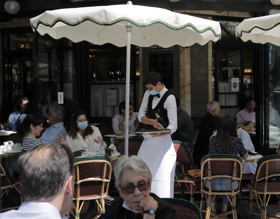 People sit on the Cafe de Flore terrace in Paris, Tuesday, June 2, 2020. Local Parisians are savoring their cafe au lait and croissants at the Left Bank's famed Cafe de Flore, or on the cobbled streets of the ancient Le Marais for the first time in almost three months. As virus confinement measures were relaxed Tuesday, cafes around France were allowed to reopen. (AP Photo/Christophe Ena)