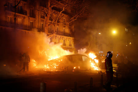 Firemen extinguish burning cars set afire by protesters wearing yellow vests, a symbol of a French drivers' protest against higher diesel fuel taxes, during clashes near the Place de l'Etoile in Paris, France, December 1, 2018. REUTERS/Stephane Mahe