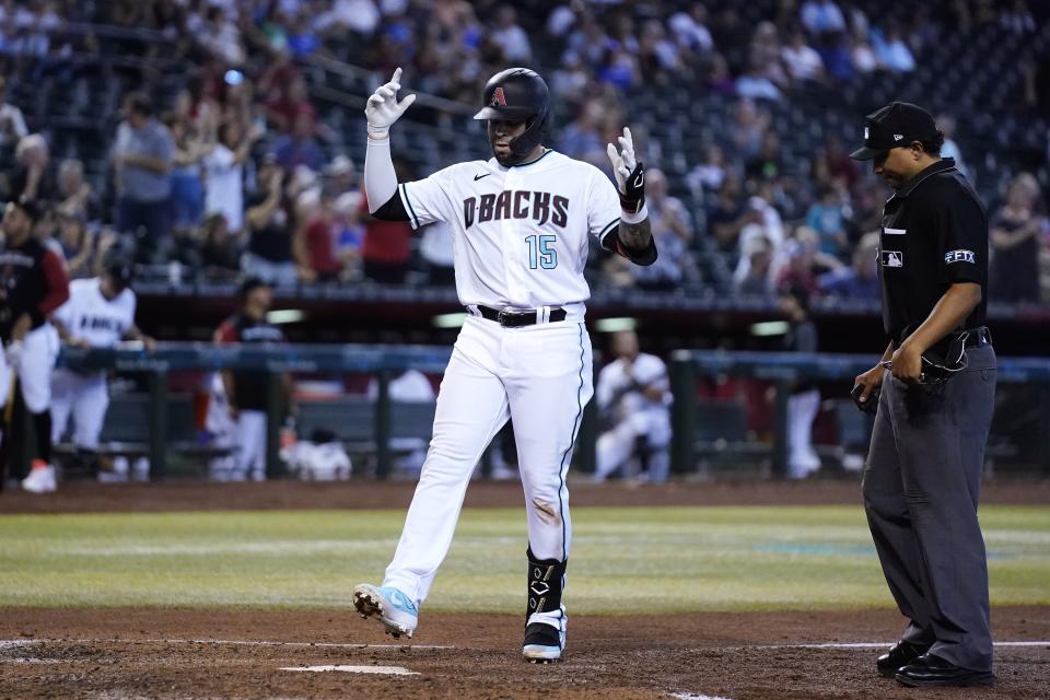 Arizona Diamondbacks' Emmanuel Rivera (15) celebrates as he arrives at home plate on his home run as umpire Erich Bacchus, right, looks on during the fourth inning of a baseball game Thursday, Aug. 11, 2022, in Phoenix. (AP Photo/Ross D. Franklin)