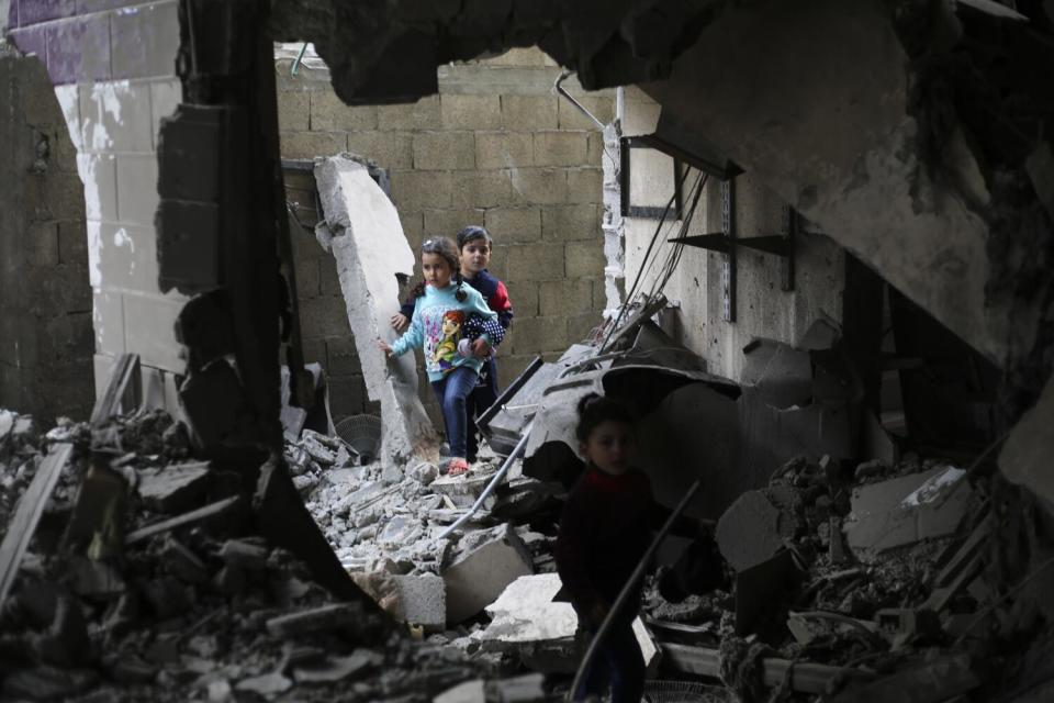 Children stand amid blasted-out walls and piles of rubble