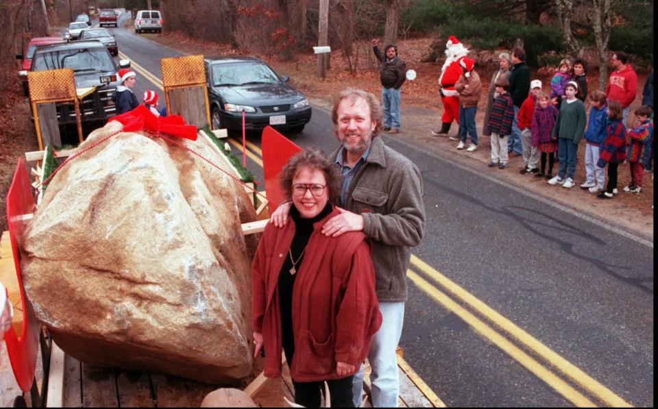 Saralee Perel and her husband Bob Daly stand next to an 18,000-pound boulder she gave him one year as a Christmas present because a decade earlier he had expressed an interest in owning one. Some of their Marstons Mills neighbors came to celebrate the gift's arrival.