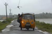 A man tries to avoid a broken electricity cable as he rides on an auto rickshaw to a safer place in Ichapuram town in Srikakulam district in the southern Indian state of Andhra Pradesh October 12, 2013. Rain and wind lashed India's east coast on Saturday, forcing more than 400,000 people to flee to storm shelters as one of the country's largest cyclones closed in, threatening to cut a wide swathe of devastation through farmland and fishing hamlets. Filling most of the Bay of Bengal, Cyclone Phailin was about 200 km (124 miles) offshore by noon on Saturday, satellite images showed, and was expected to hit land by nightfall. REUTERS/Adnan Abidi (INDIA - Tags: ENVIRONMENT DISASTER)