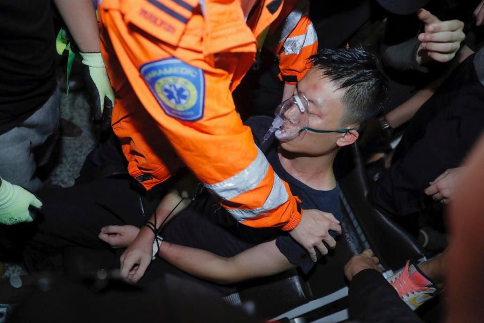 A medical staffer helps a detained man at Hong Kong International Airport who protesters claimed was a police officer from mainland China on Tuesday, Aug. 13, 2019.  (AP Photo/Kin Cheung)