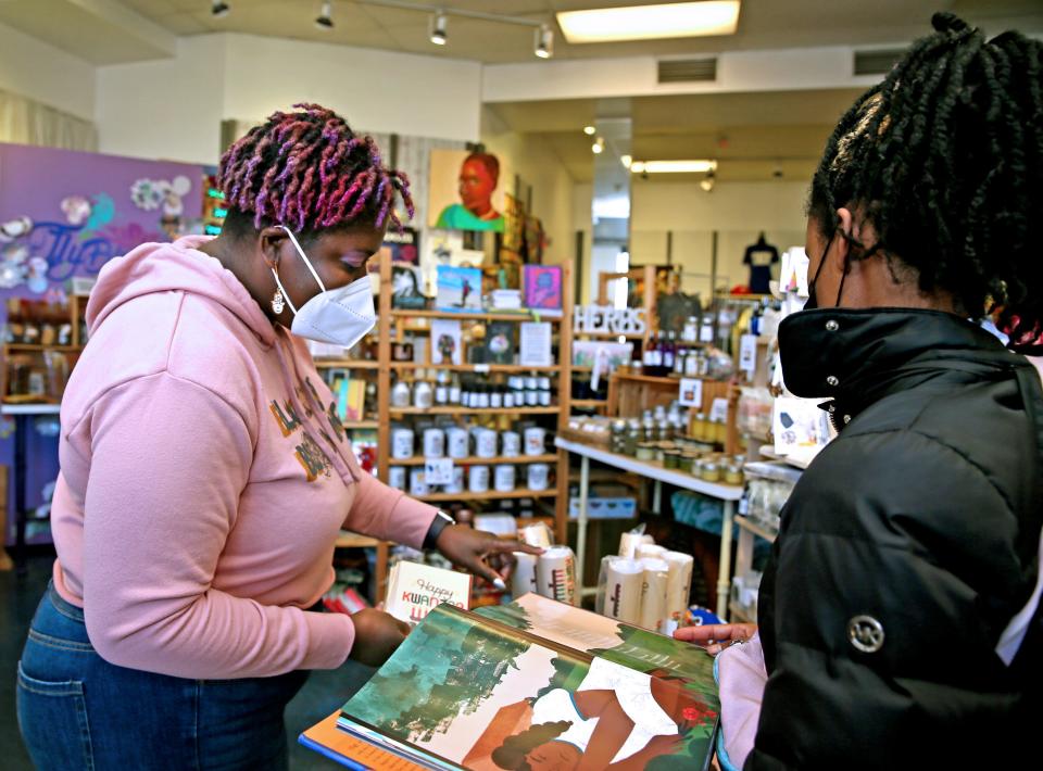 Tiffany Miller, owner at FlyBlooms at Bronzeville Collective, shows a customer Kwanzaa holiday gift items on Friday, Nov. 25, 2022 on at 339 W. North Ave., in Milwaukee. Miller is also a co-owner of Bronzeville Collective.