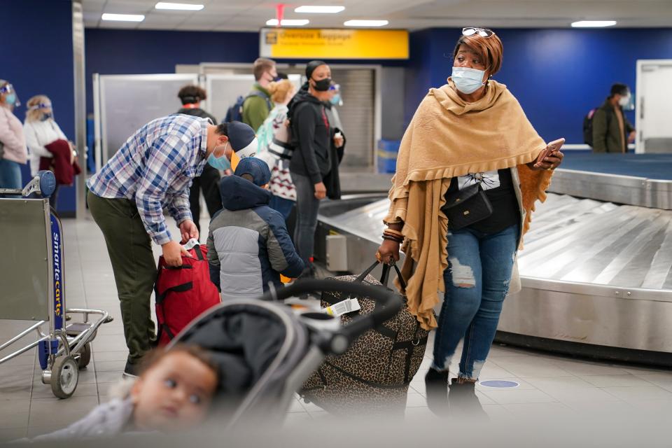 Travelers wearing masks to prevent the spread of COVID-19 prepare to leave the Terminal C baggage claim area at LaGuardia Airport on Wednesday, Nov. 25, 2020.