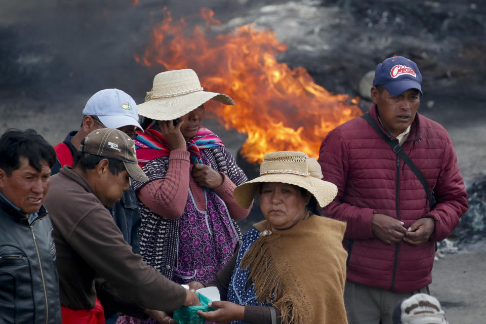 Supporters of former President Evo Morales chew coca leaves at a barricade in El Alto, on the outskirts of La Paz, Bolivia, Tuesday, Nov. 19, 2019. Morales' backers have taken to the streets asking for his return since he resigned on Nov. 10 under pressure from the military after weeks of protests against him over a disputed election he claim to have won. (AP Photo/Natacha Pisarenko)