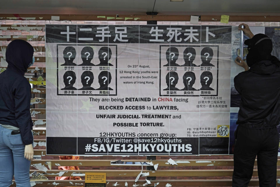 In this Tuesday, Sept. 29, 2020 photo, university students put up posters to demand of releasing the 12 Hong Kong activists detained at sea by Chinese authorities, at a "Lennon wall" in the University of Hong Kong. Police in Hong Kong say they have arrested nine people on suspicion of providing funds and other assistance to a group of 12 who sought to flee the territory by boat in August but were intercepted by Chinese authorities. (AP Photo/Kin Cheung)