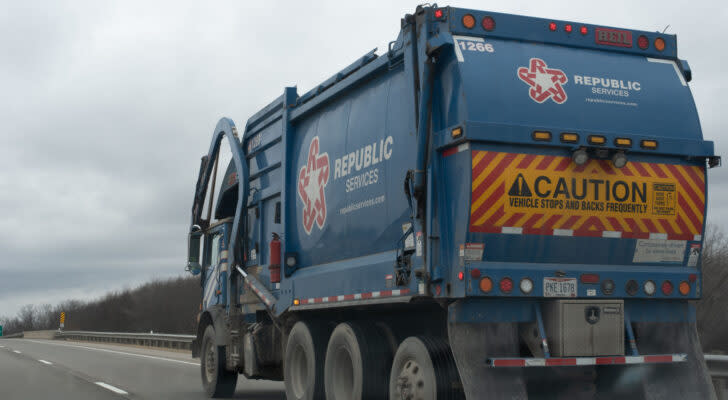 An image of a blue Republic Services trash truck driving on the highway on a cloudy day.