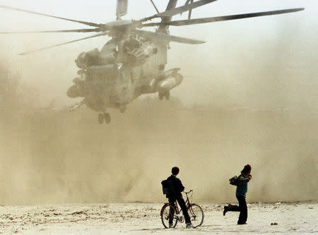 FILE PHOTO: Two Albanians watch a U.S. marine CH53 Super Stallion helicopter take off from Golame beach near the port town of Durres, March 16. U.S. marines stormed out of helicopters onto Golame Beach to rescue American, Turkish and Italian citizens from the chaos of Albania as many frantic Albanians attempted to jump onboard. The helicopters kicked up blizzards of stinging sand as they landed and marines used rifle butts to beat off Albanians trying to board the aircraft and escape their country. REUTERS/Yannis Behrakis/File photo