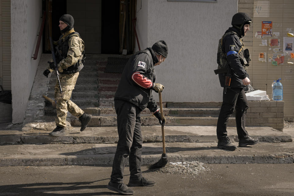 A man sweeps broken glass after parts of a Russian missile, shot down by Ukrainian air defense, landed on a nearby apartment block, according to authorities, in Kyiv, Ukraine, Thursday, March 17, 2022. Russian forces destroyed a theater in Mariupol where hundreds of people were sheltering Wednesday and rained fire on other cities, Ukrainian authorities said, even as the two sides projected optimism over efforts to negotiate an end to the fighting. (AP Photo/Vadim Ghirda)